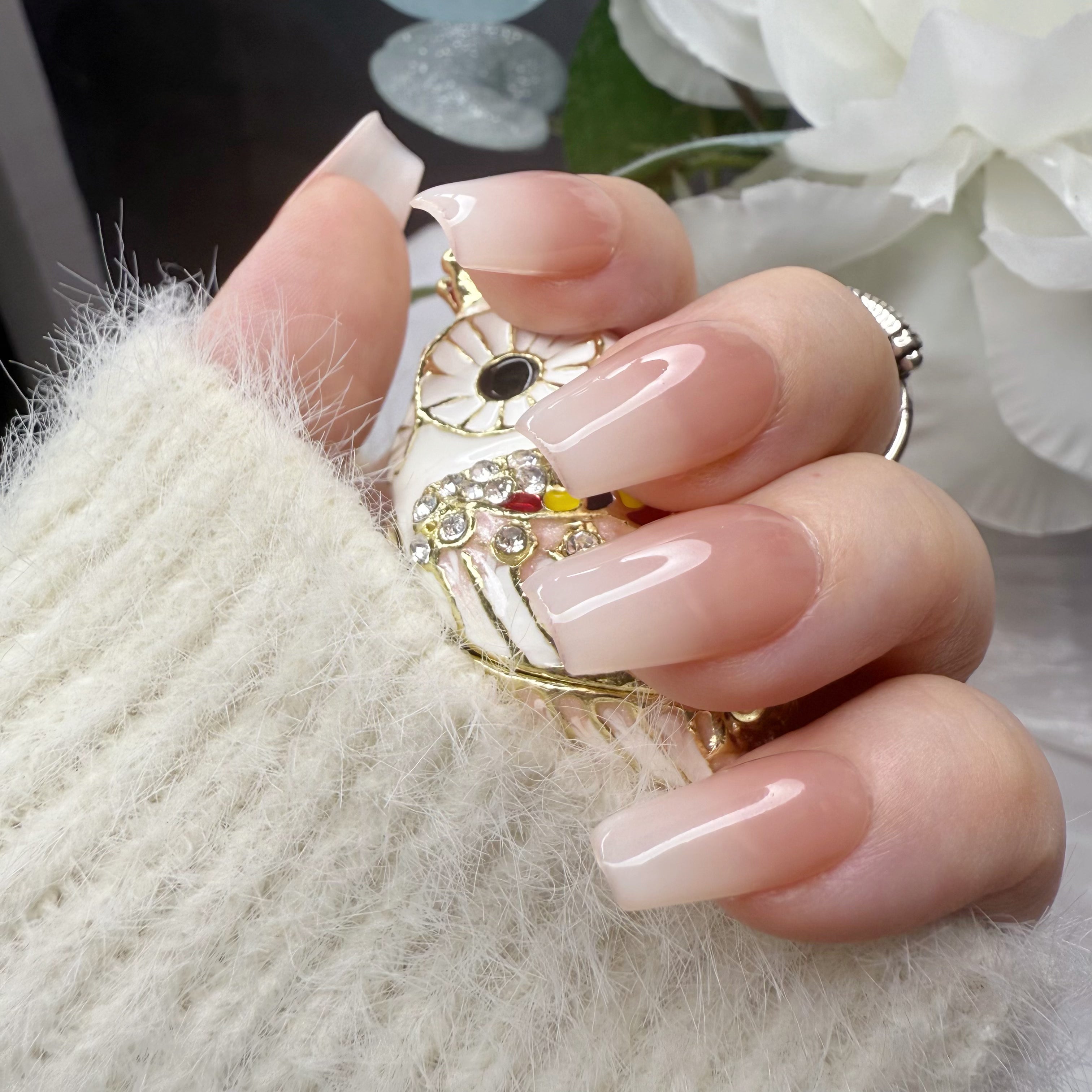 Medium square press-on nails featuring a glossy nude-to-white ombre gradient with a seamless, high-shine transition. (Lifestyle shot)