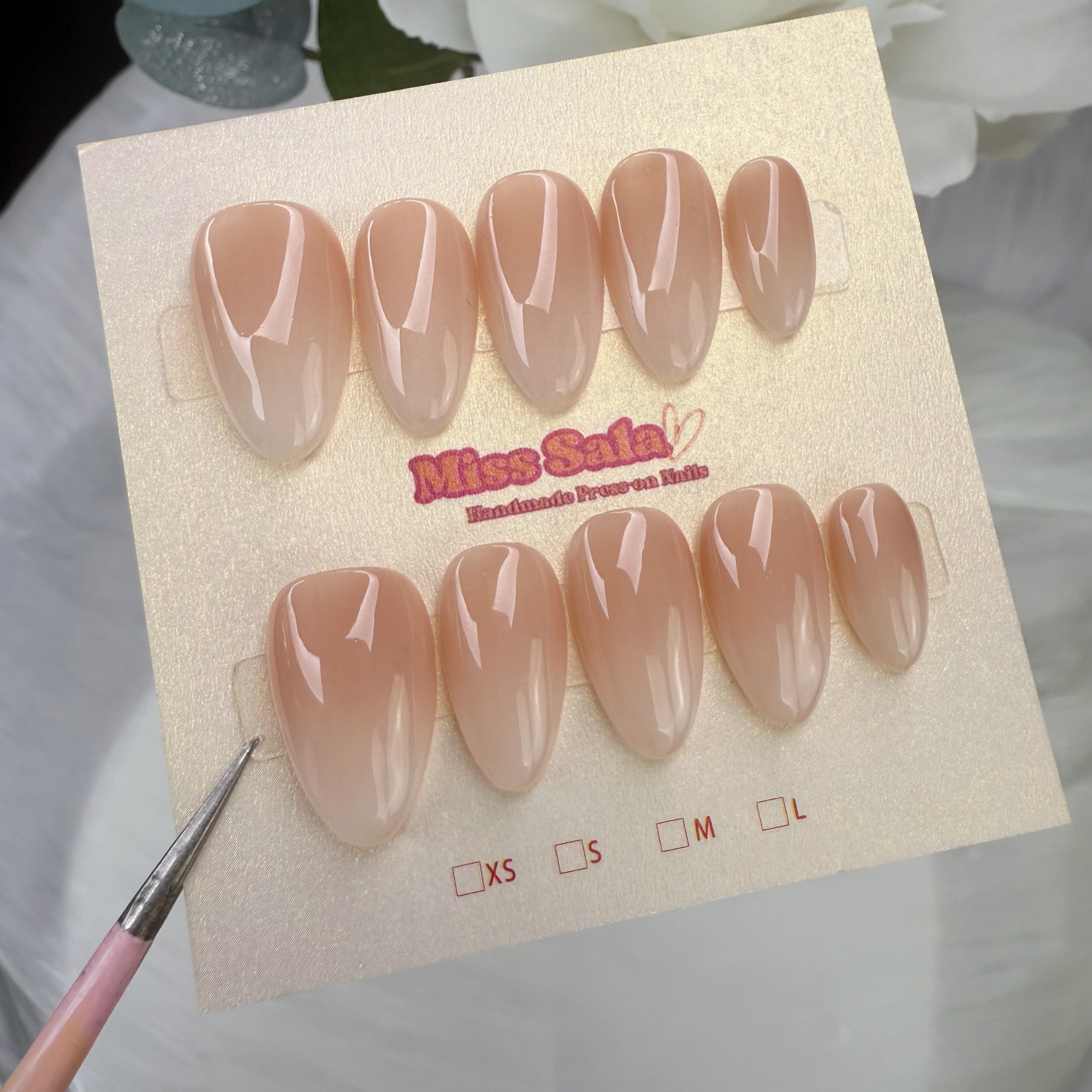 Short almond-shaped press-on nails with a glossy nude-to-white ombre gradient finish, featuring a seamless transition from a soft tan base to milky white tips.