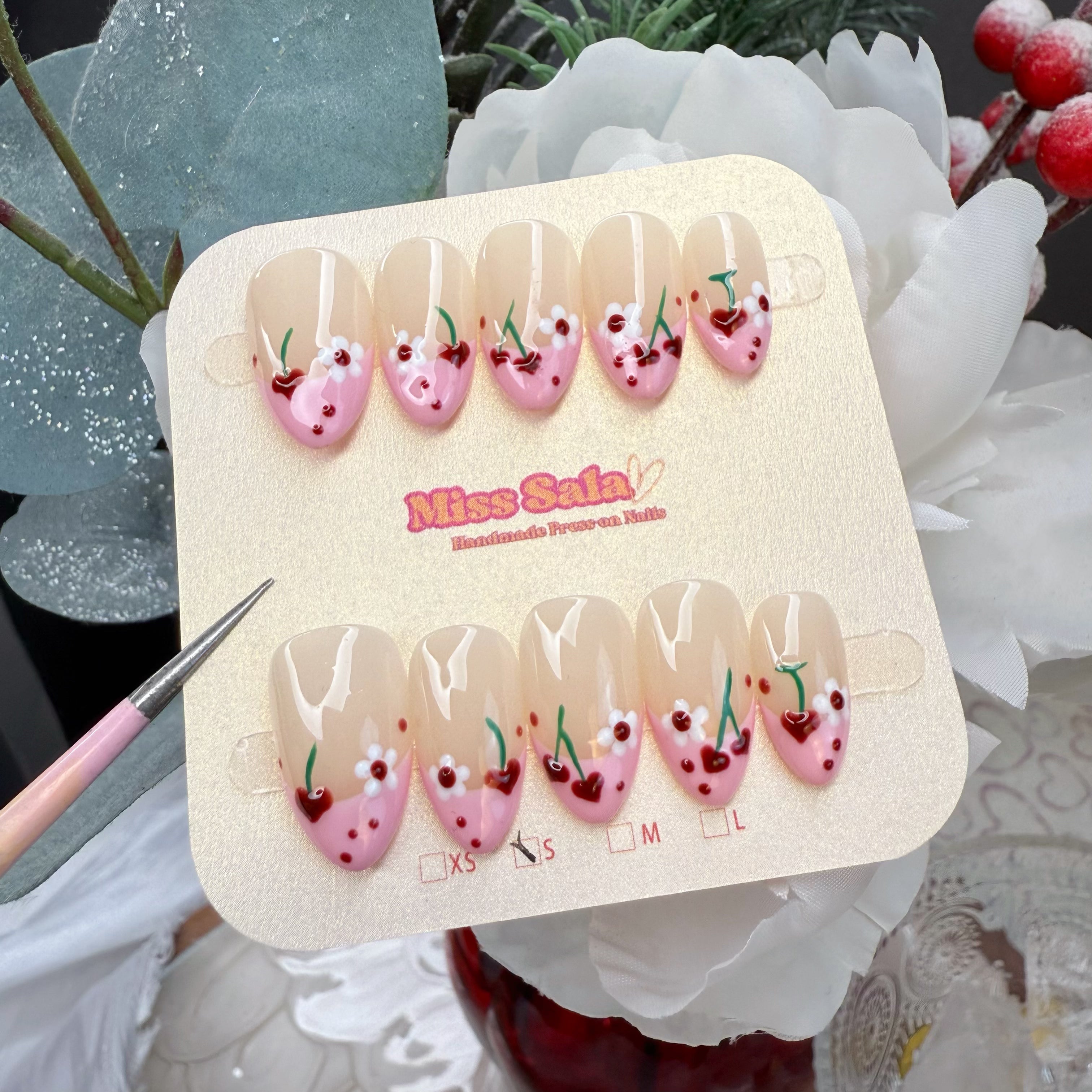 Almond-Shaped Press-On Nails with Nude Base, Pink French Tips, Hand-Painted Red Heart Cherries, White Flowers, and Red Sprinkle Details