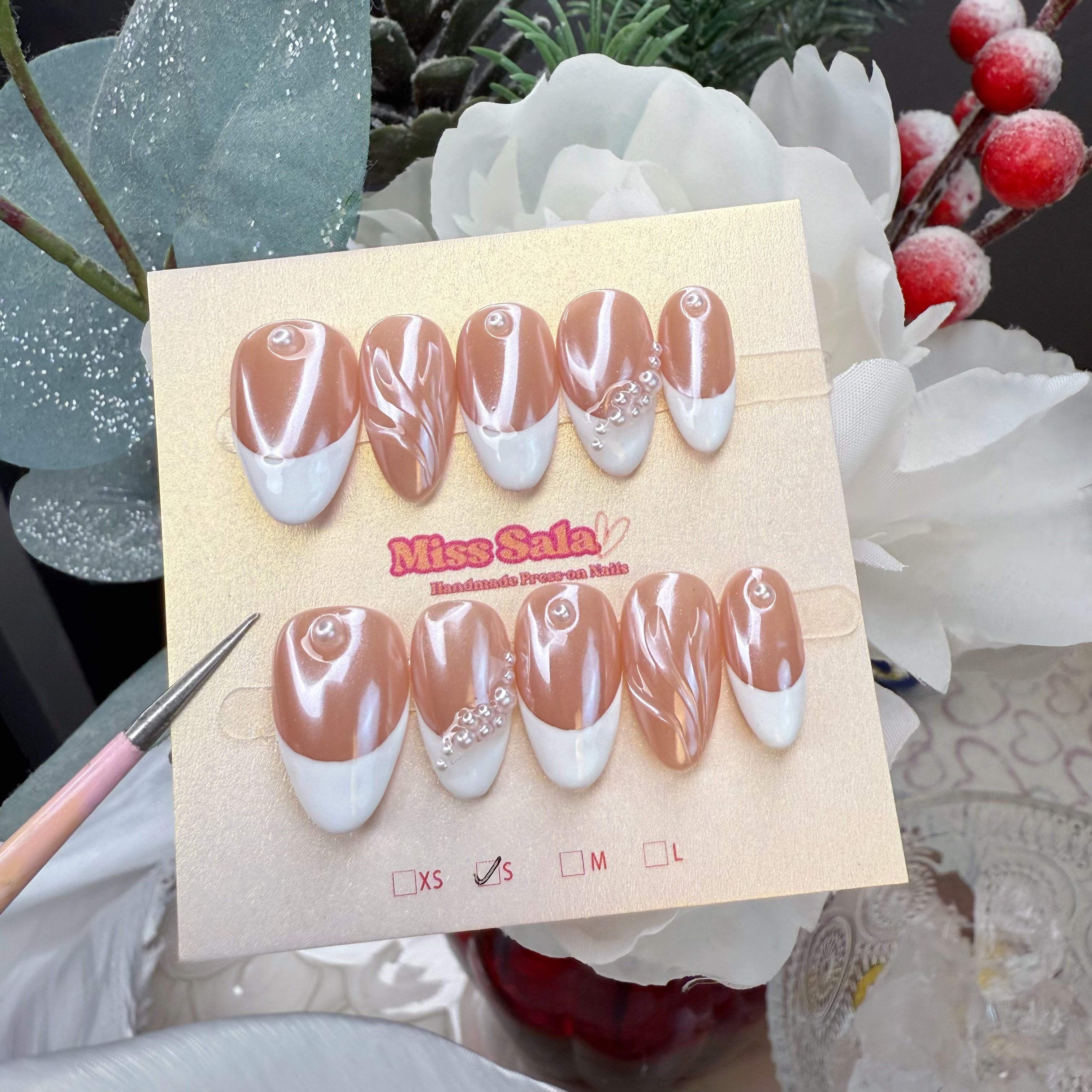 Almond-shaped press-on nails with a rose-gold chrome base, crisp white French tips, 3D textured marble swirls, and white pearl accents.