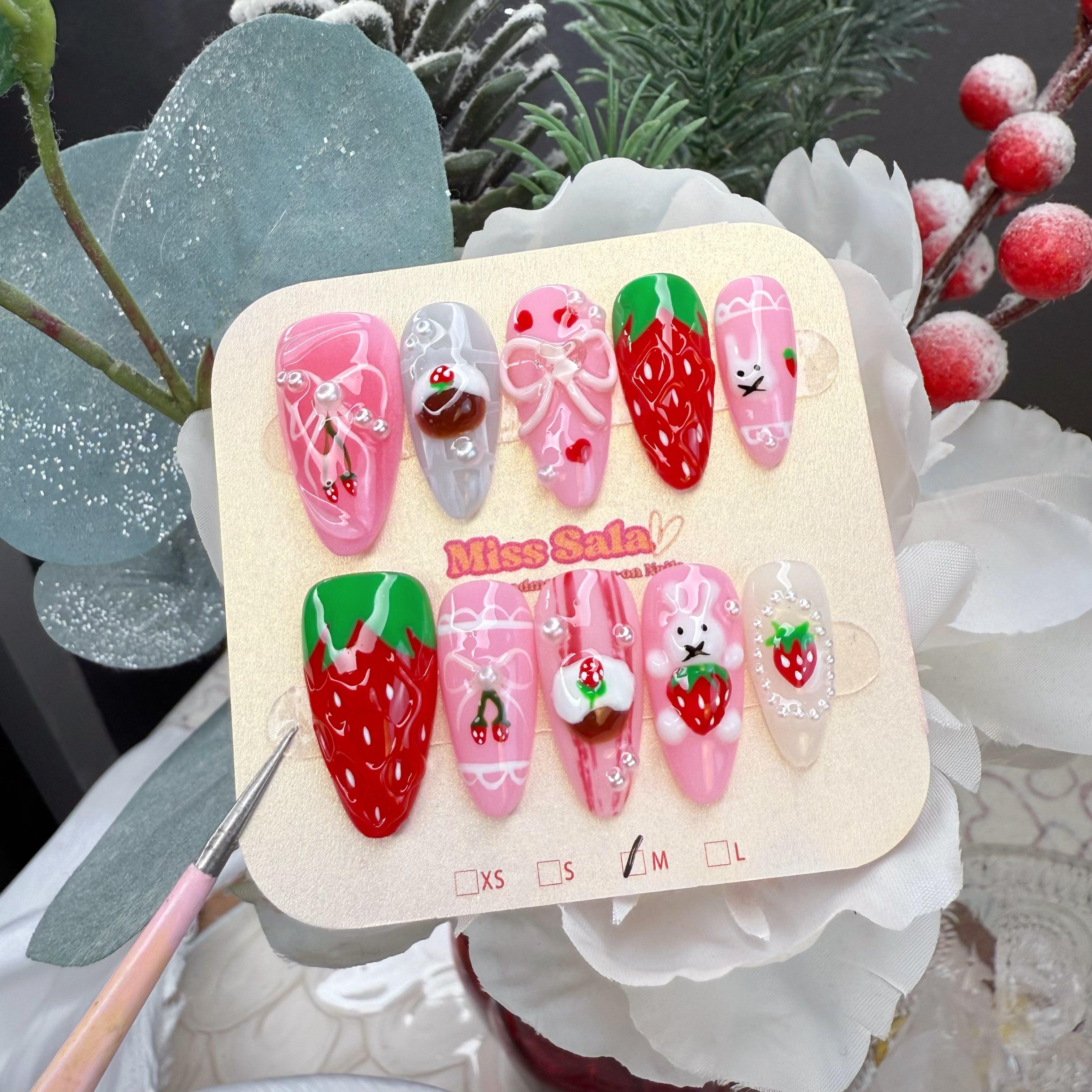 Almond-shaped press-on nails featuring 3D strawberry charms, 3D bunnies, miniature pudding accents, and hand-painted lace on a pink and white base.