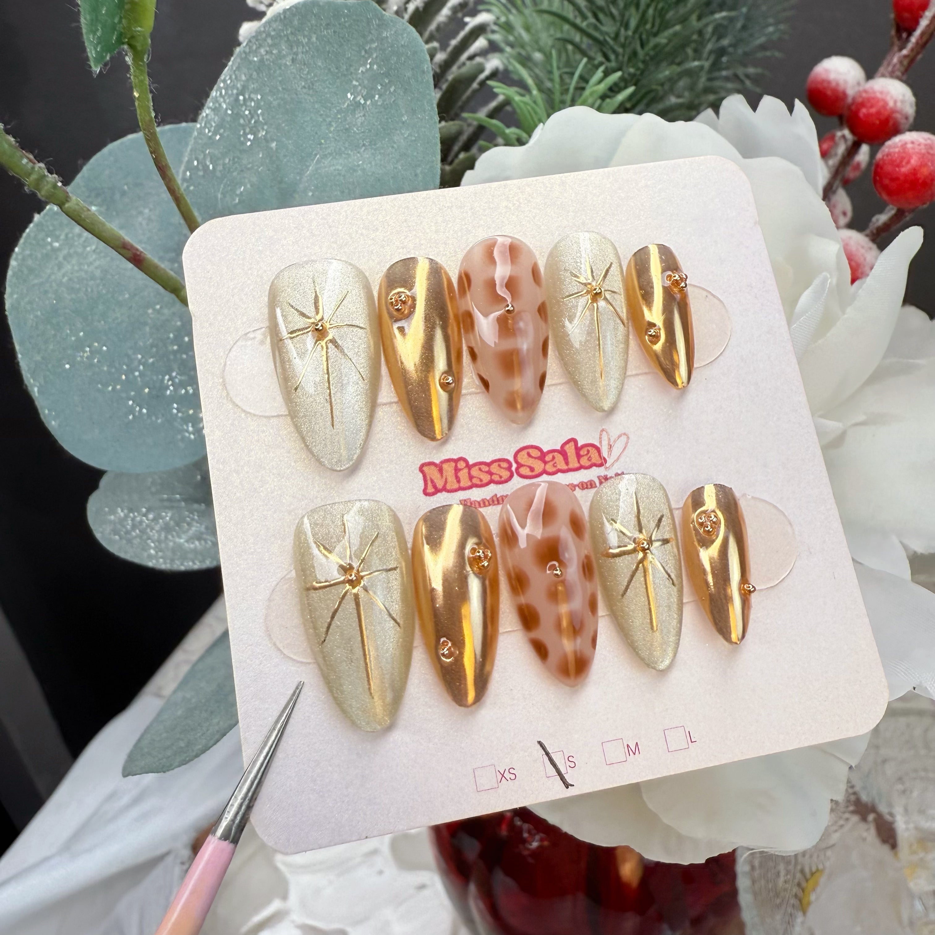 Almond-Shaped Press-On Nails with Champagne Shimmer Bases, Gold Chrome Finishes, Hand-Painted Leopard Print, and 3D Gold Starburst Accents