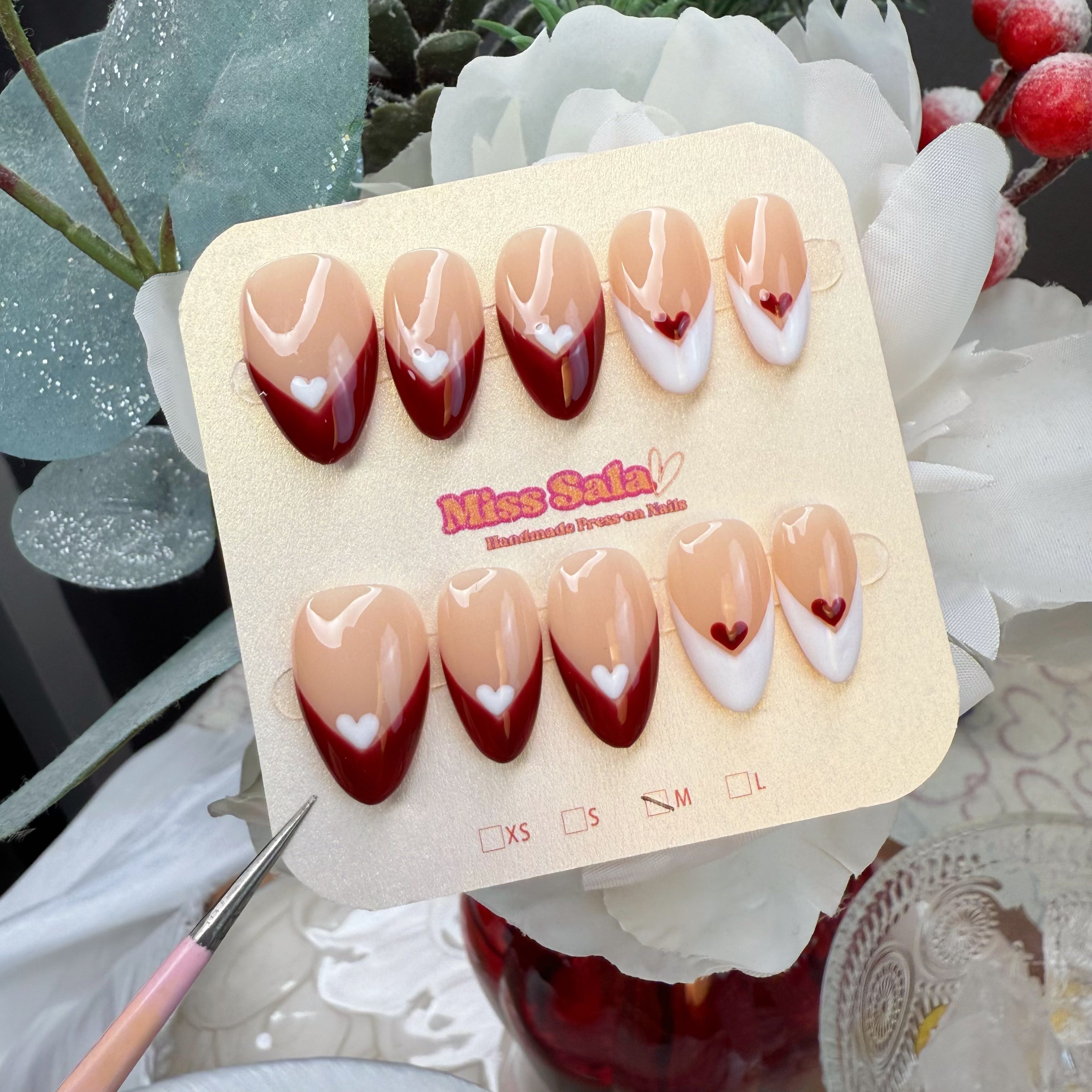 Almond-Shaped Press-On Nails with Nude Base, Deep Wine Red and White French Tips, and Delicate Hand-Painted Heart Details