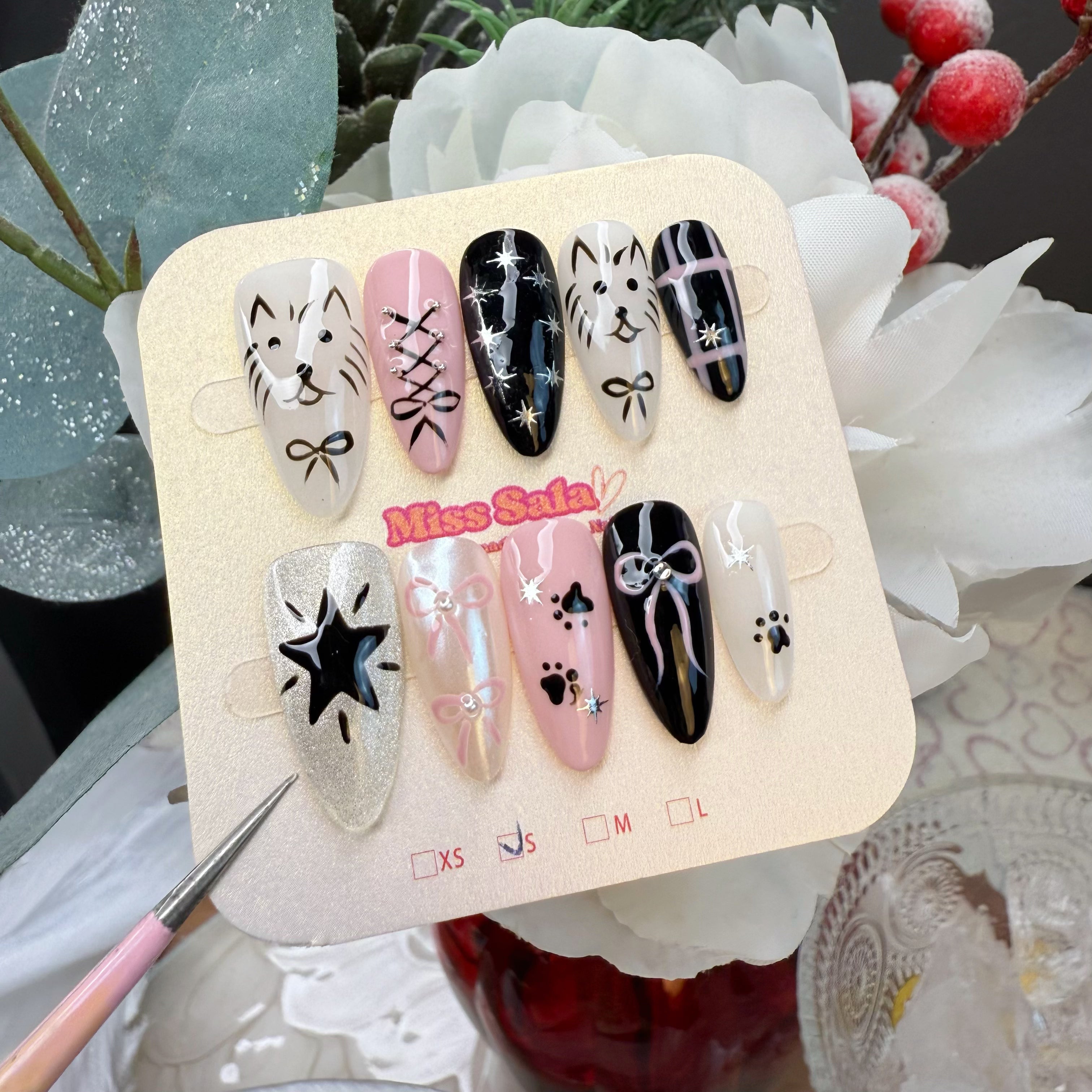 Almond-Shaped Press-On Nails in Black and Pink featuring Hand-Painted Cat Faces, Corset Lacing, Bows, Paw Prints, and Shimmering Silver Starbursts