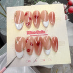 Almond-shaped press-on nails with a glossy nude base, featuring hand-painted red lips, a red heart aura with gold rays, and a white French tip with gold stars.
