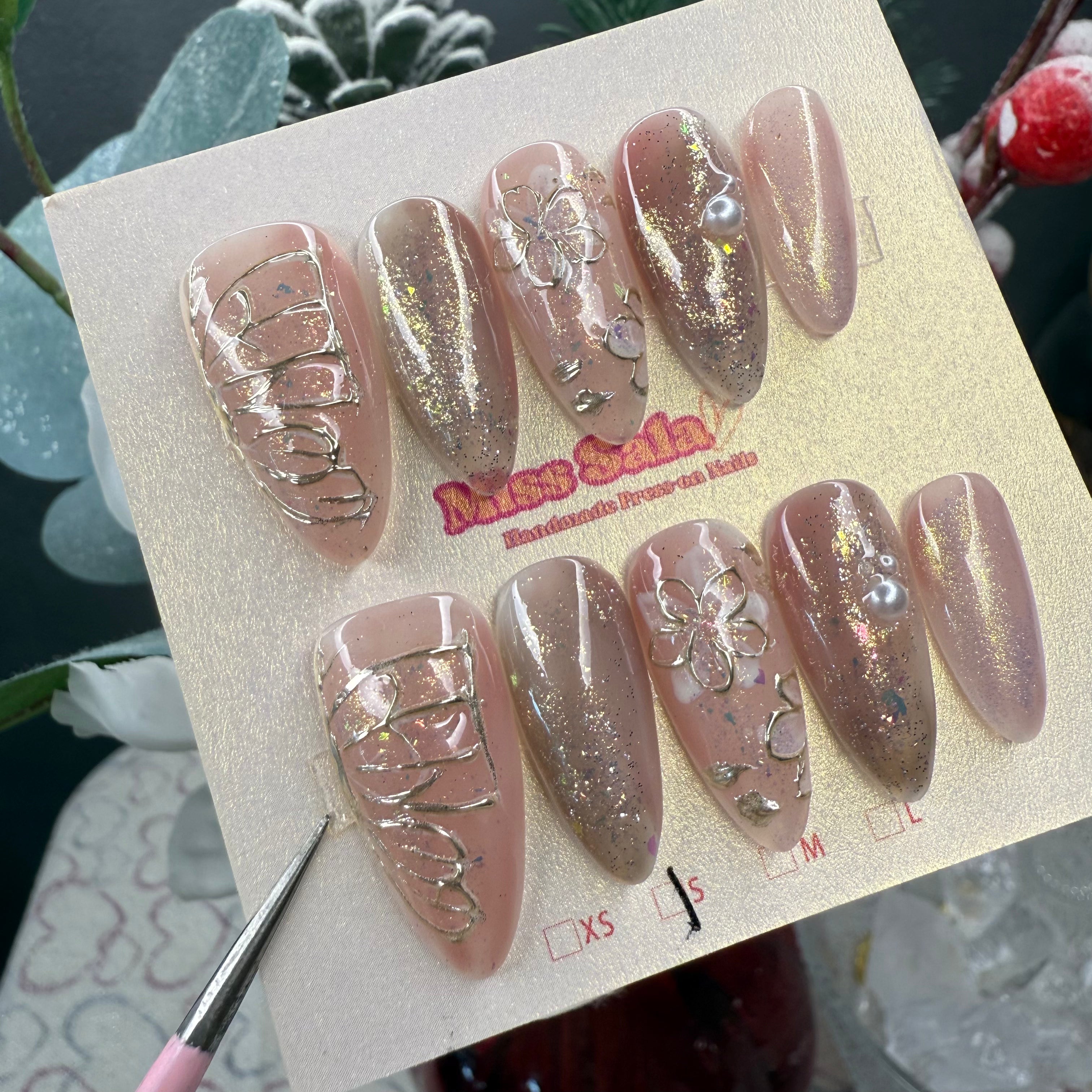 Butterfly Dreams Press-On Nails - Detailed View of Nudy-Pink Shimmer Almond Nails with gold Butterfly Wings, Floral Art, and Iridescent Glitter